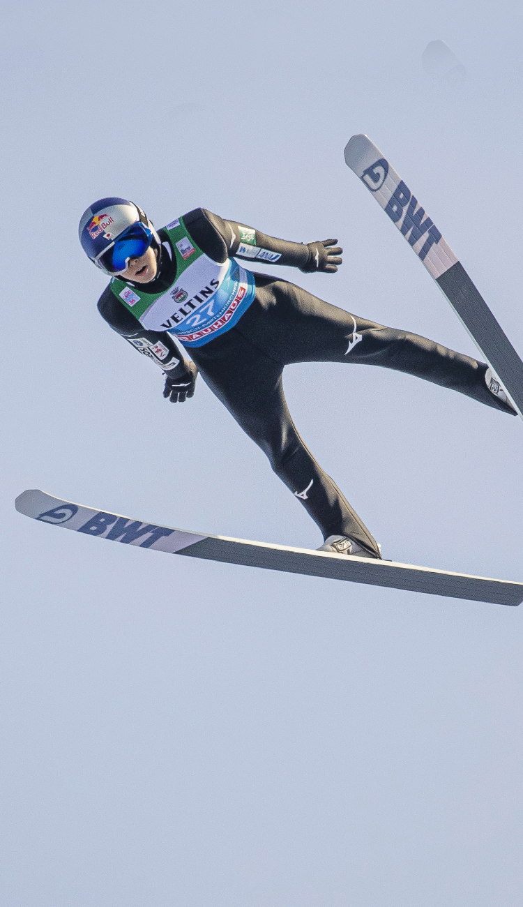 写真：雄大な山脈を背景にスキージャンプで滑空している小林陵侑